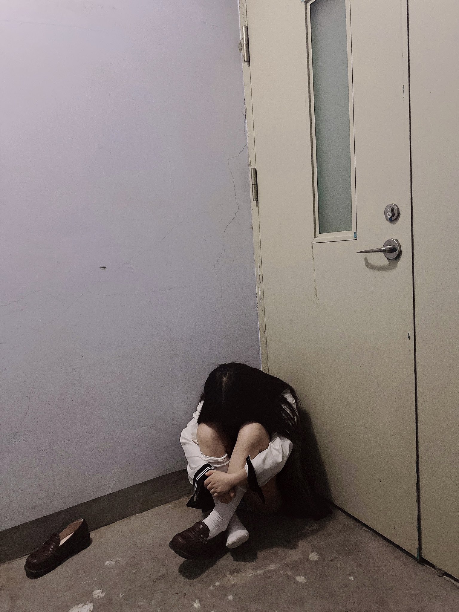 女人坐在一间房间的地板上。