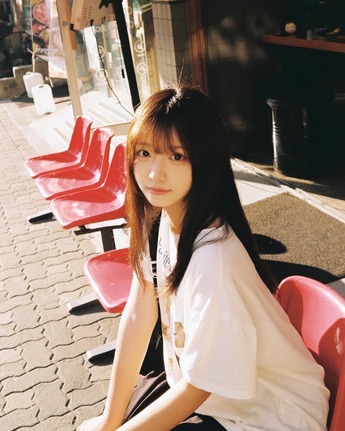 女孩坐在红色的椅子上。