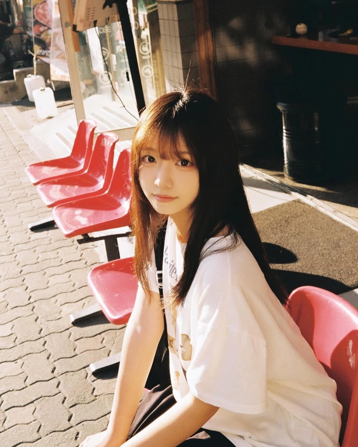 女孩坐在红色的椅子上。