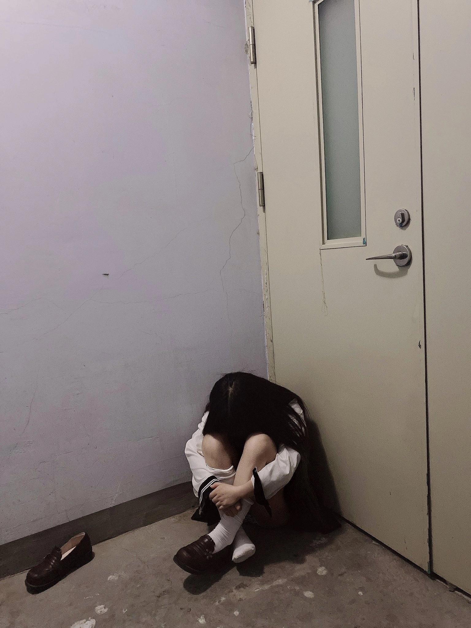 女人坐在一间房间的地板上。