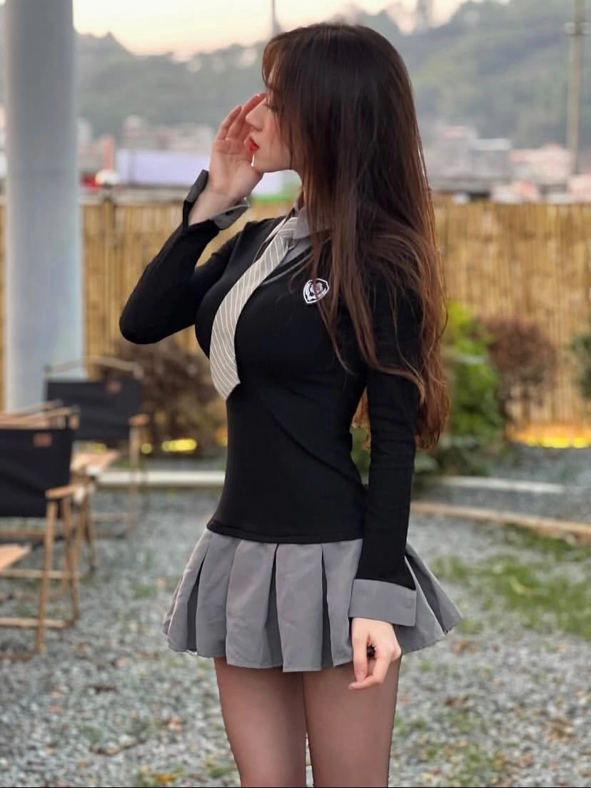 女人穿着一件黑白衬衫和一件灰色裙子。