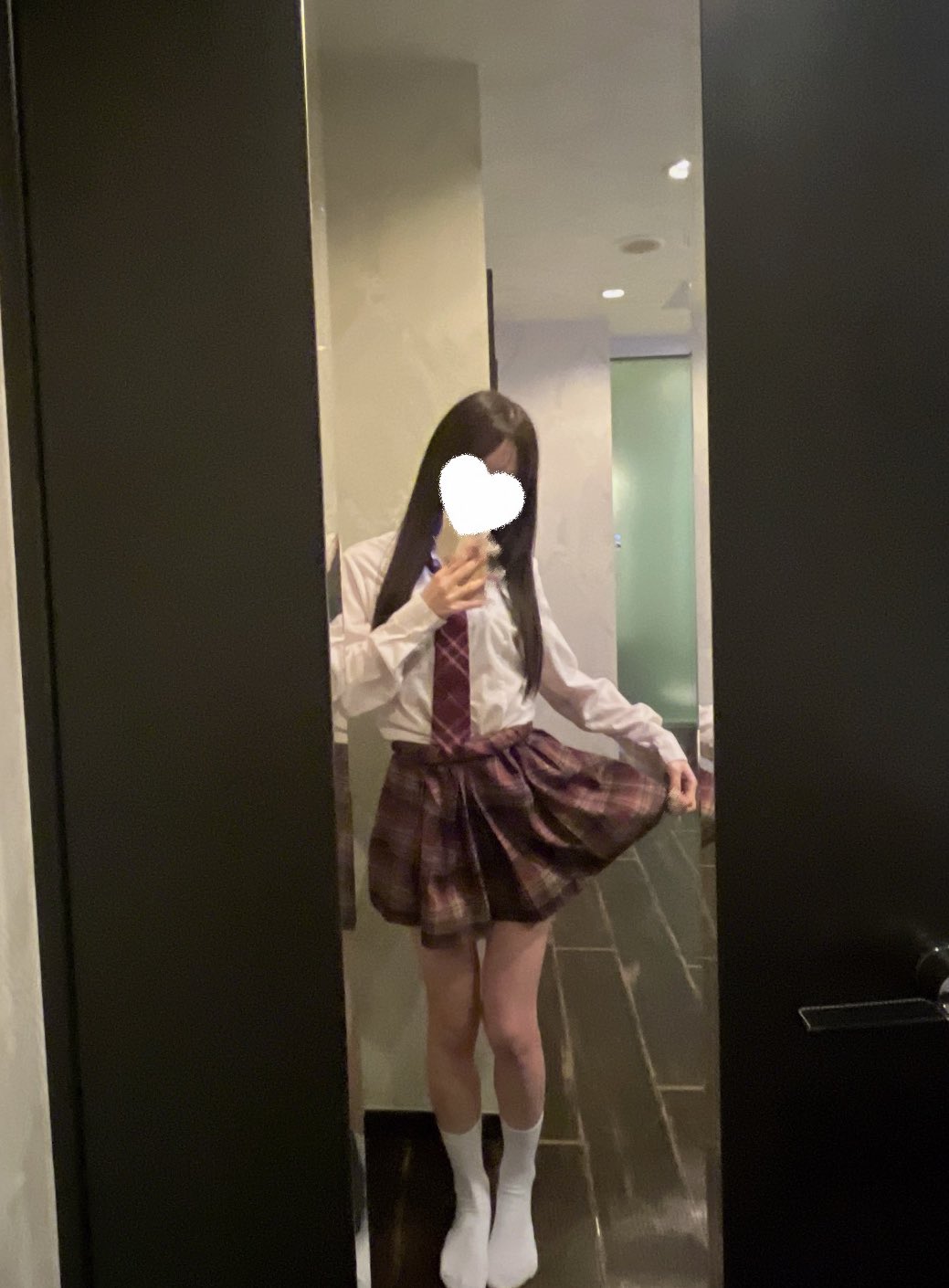 一位穿着白色衬衫和红色领带的女人在镜子里拍了一张自拍。