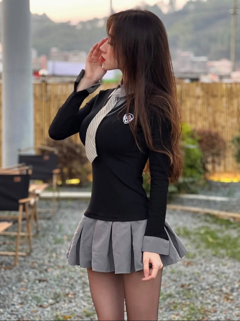 女人穿着一件黑白衬衫和一件灰色裙子。