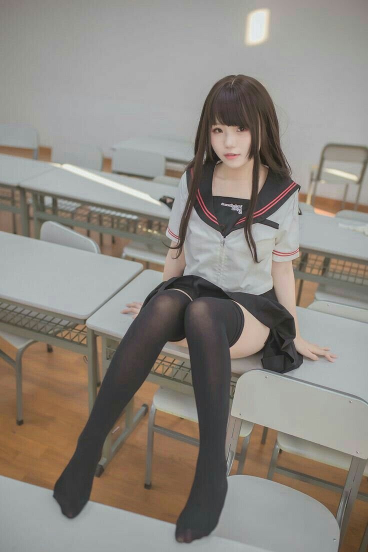 穿着黑白水手服的女孩坐在椅子上。