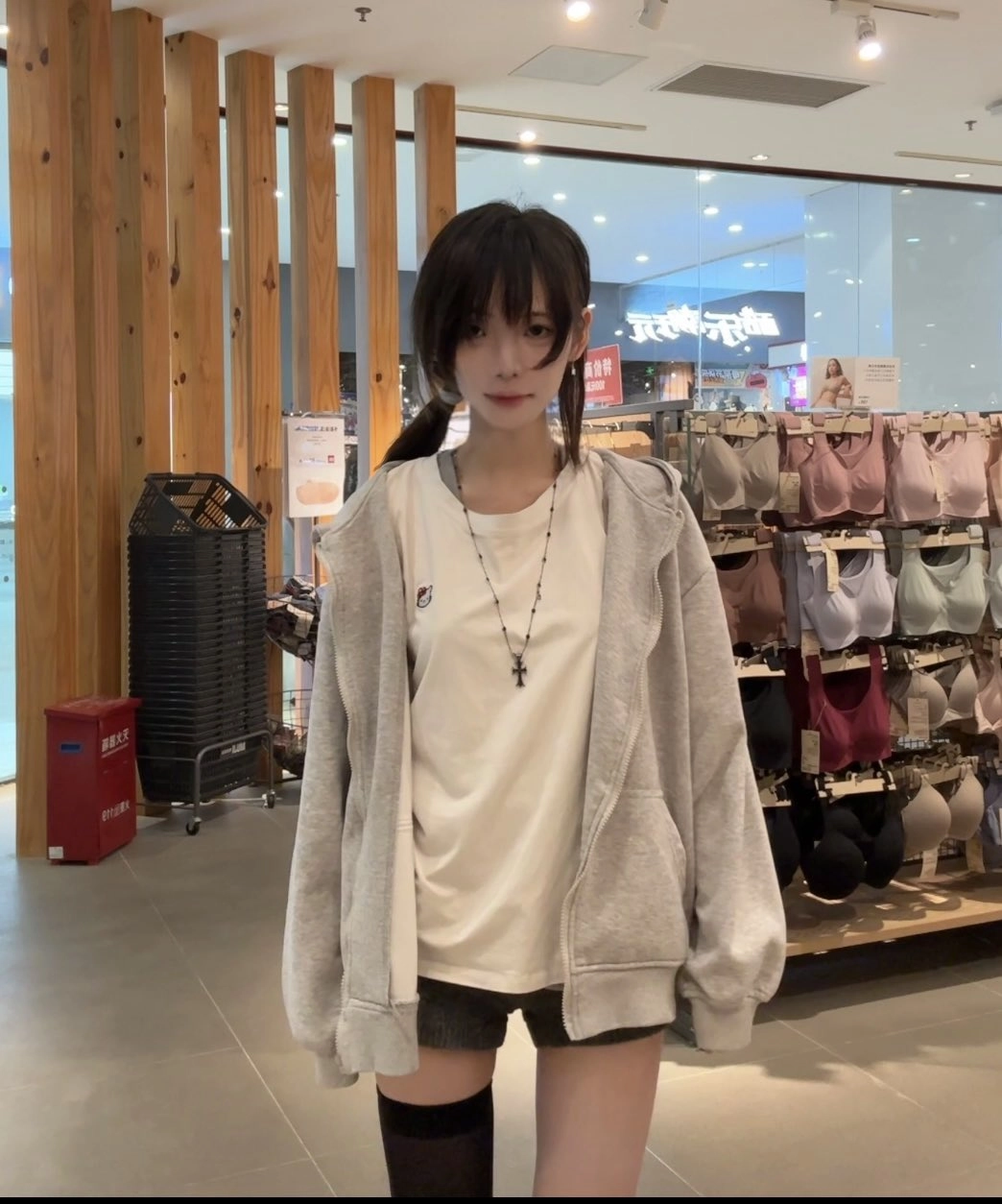 一位穿着白色衬衫和灰色衬衫的女人站在商店的展示台前。