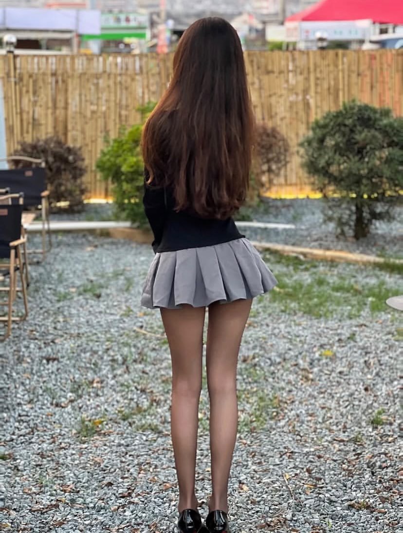 女人穿着一件黑白衬衫和一件灰色裙子。