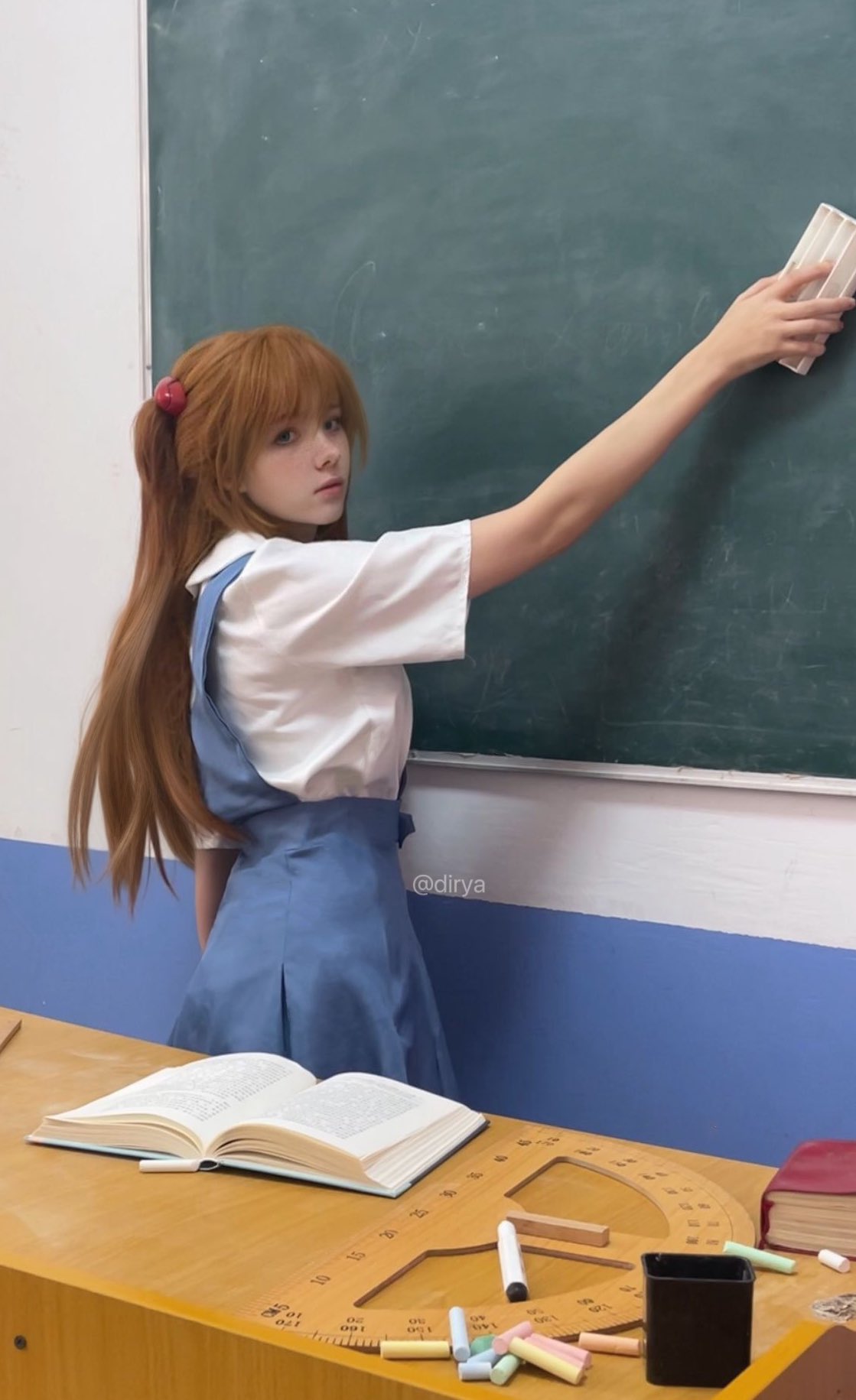 一位穿着一只马尾巴和一件蓝色的裙子的女孩站在板前面。