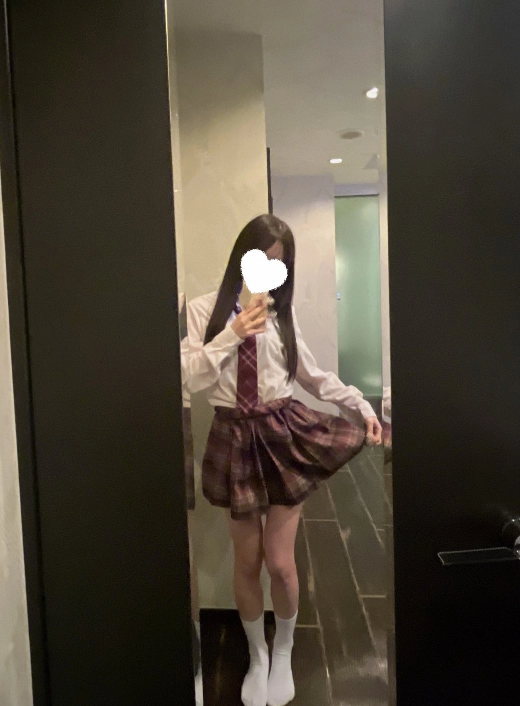 一位穿着白色衬衫和红色领带的女孩在镜子里拍了一张自拍。