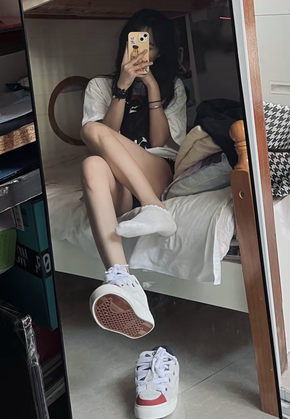 一位穿着白色衬衫和黑色手的女人坐在床上。