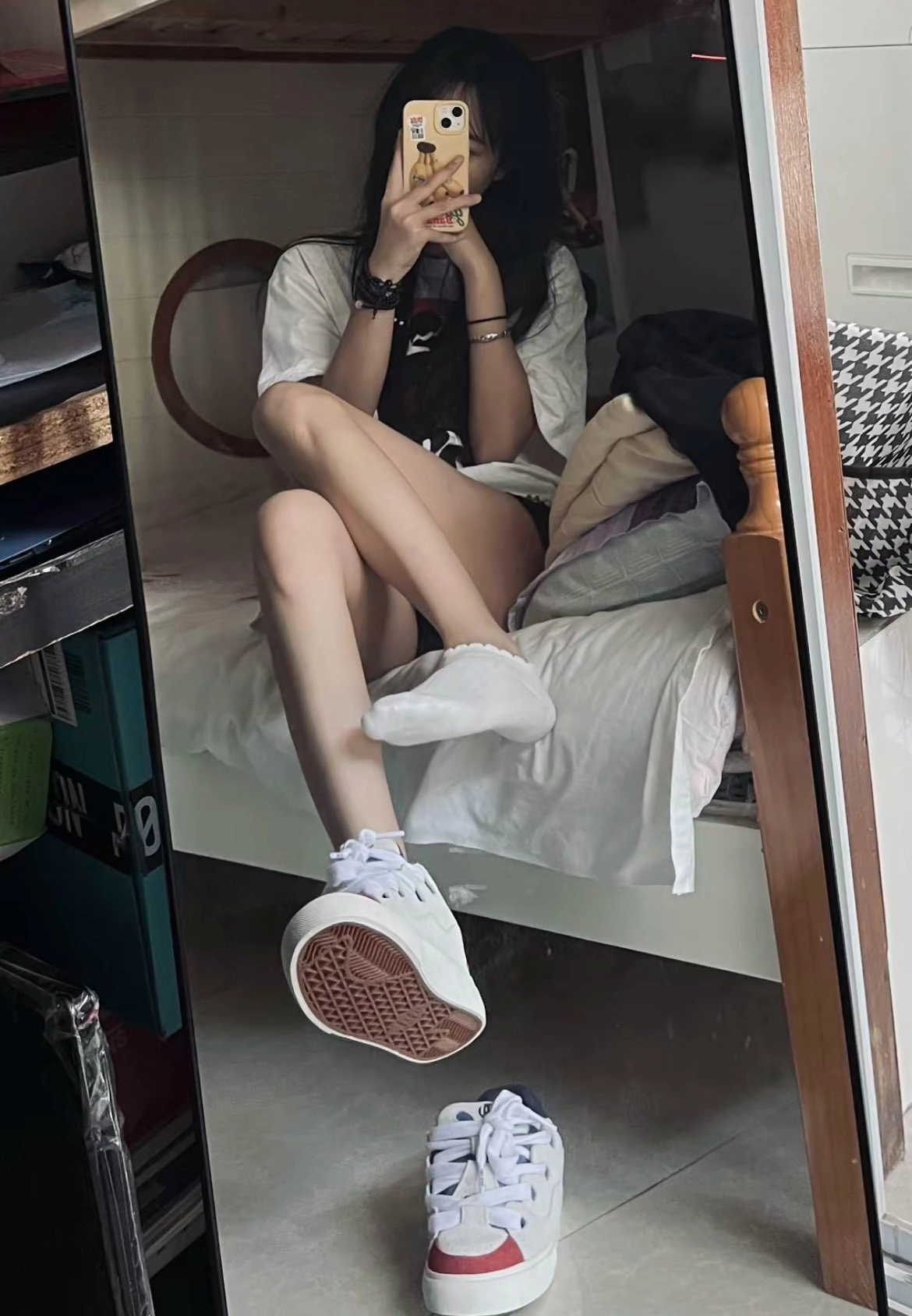 一位穿着白色衬衫和黑色手的女人坐在床上。