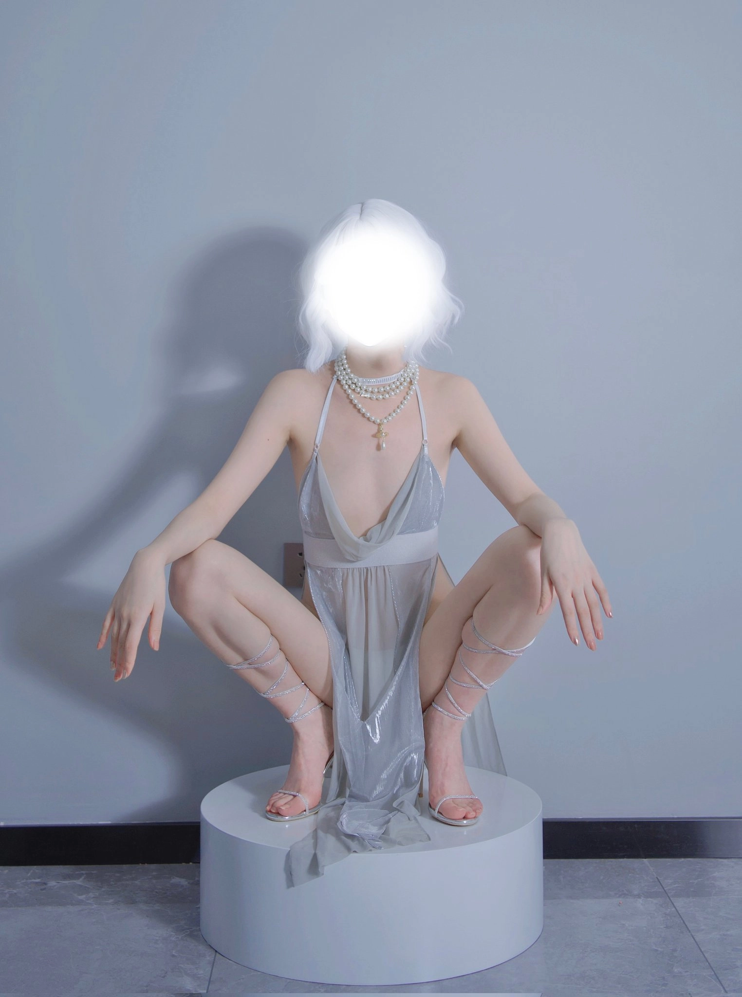 一位穿着白色裙子和珍珠的女人坐在白色脚踏板上。