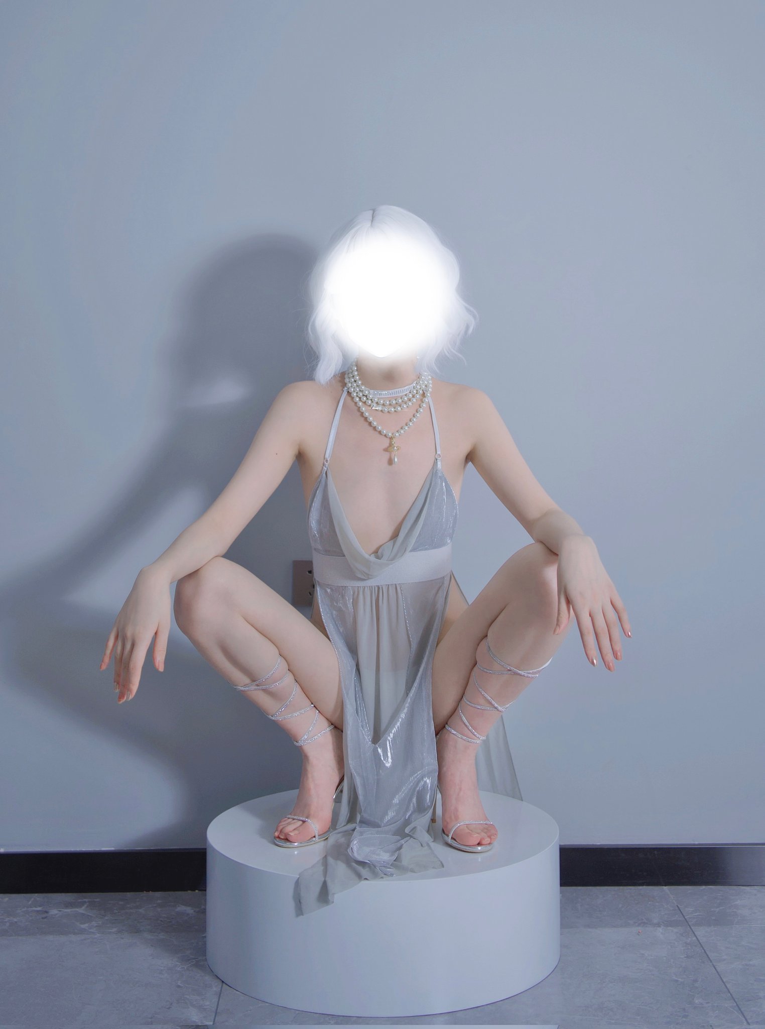 一位穿着白色裙子和珍珠的女人坐在白色脚踏板上。