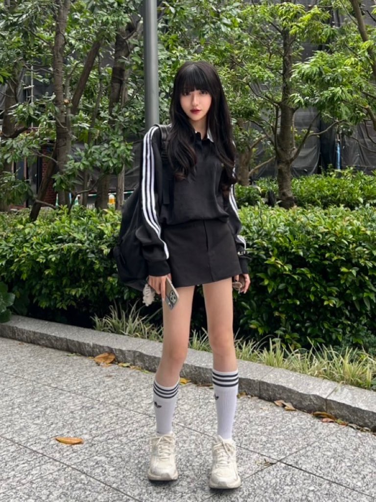 一位穿着黑色衬衫和白色袜子的女人站在走廊上。