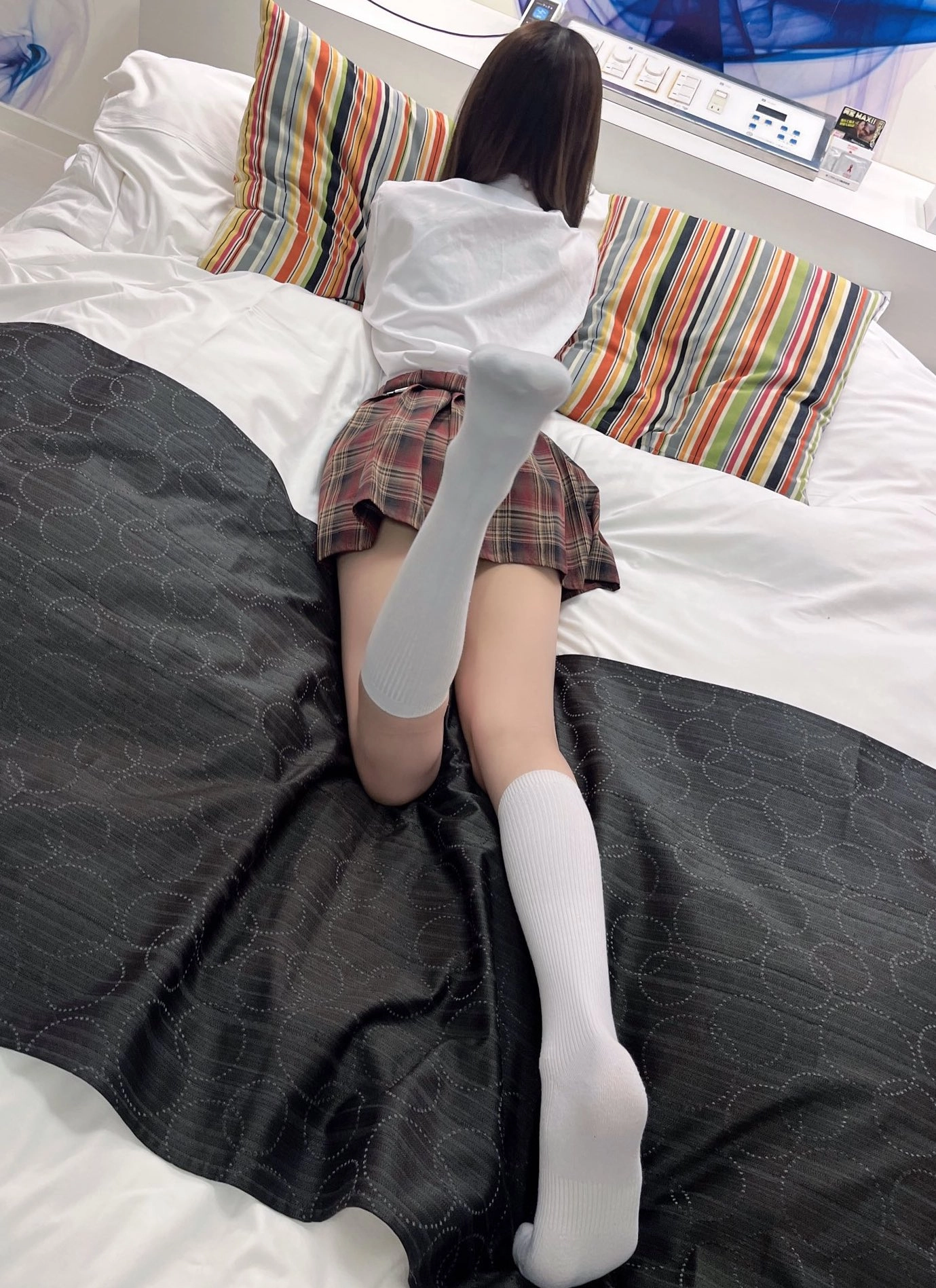 穿着白色衬衫和裙的女孩躺在床上。