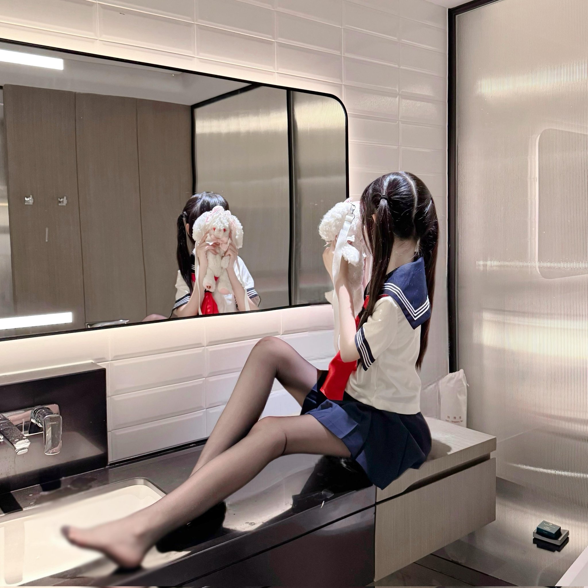 穿着蓝色水手服的女孩坐在镜子前。