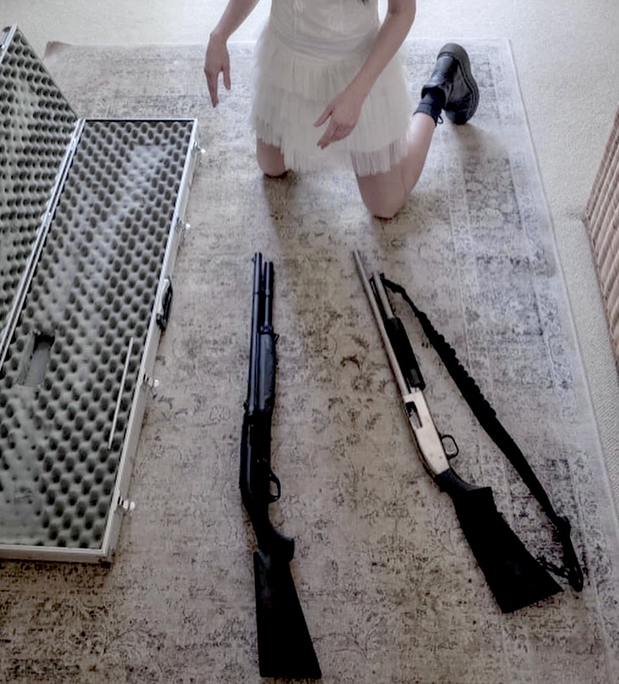 女人跪在一张带枪的地毯上。
