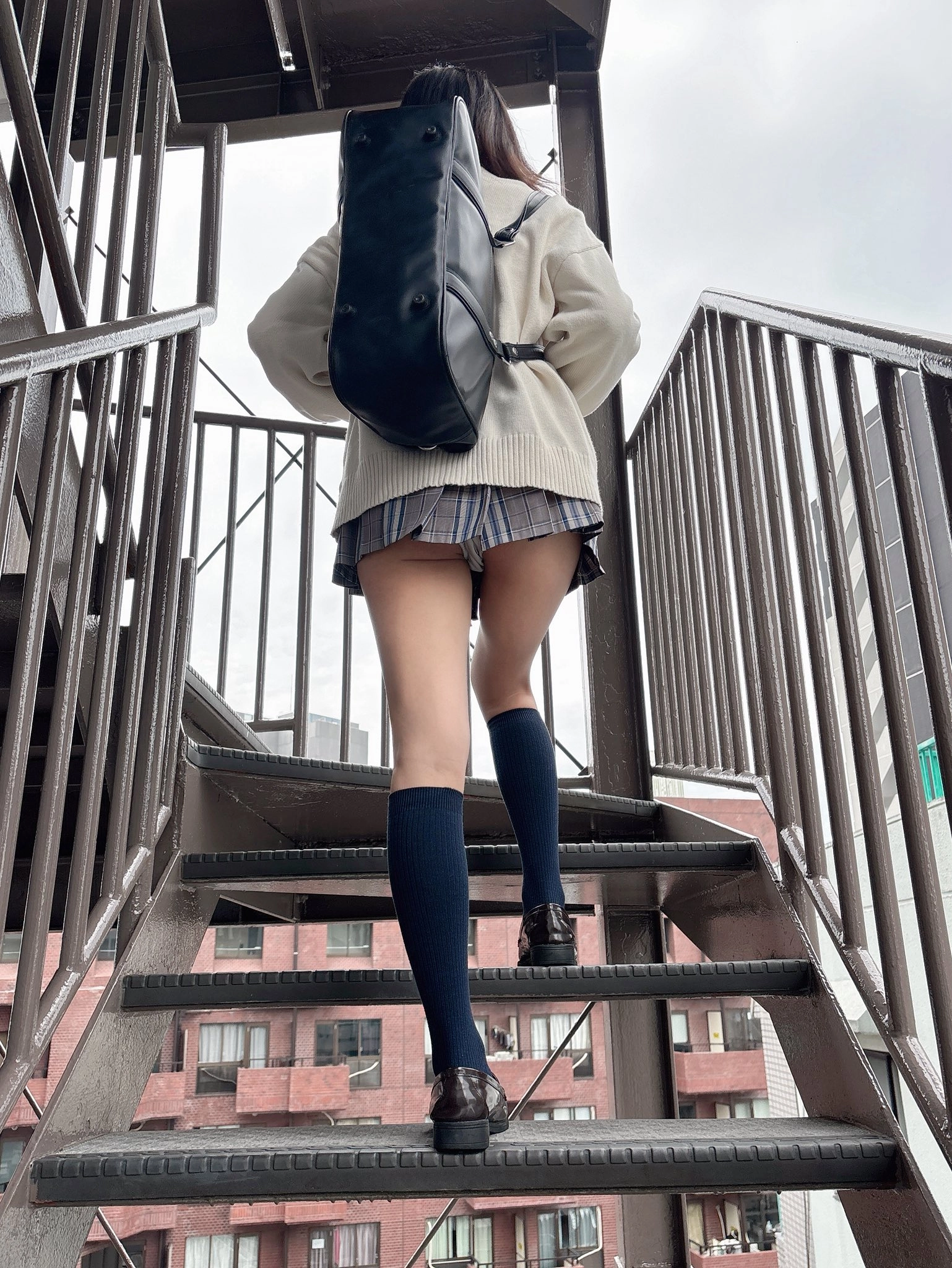 穿着白色衬衫和蓝色袜子的女人带着一个黑色背包。