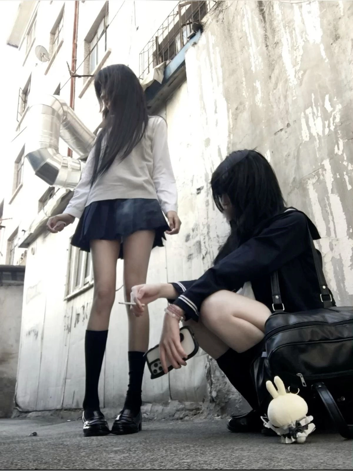 两个女孩抽烟,其中拿着手机。