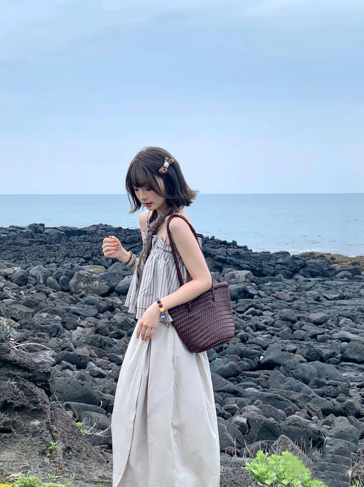 女人穿着白色裙子,带着棕色钱包。