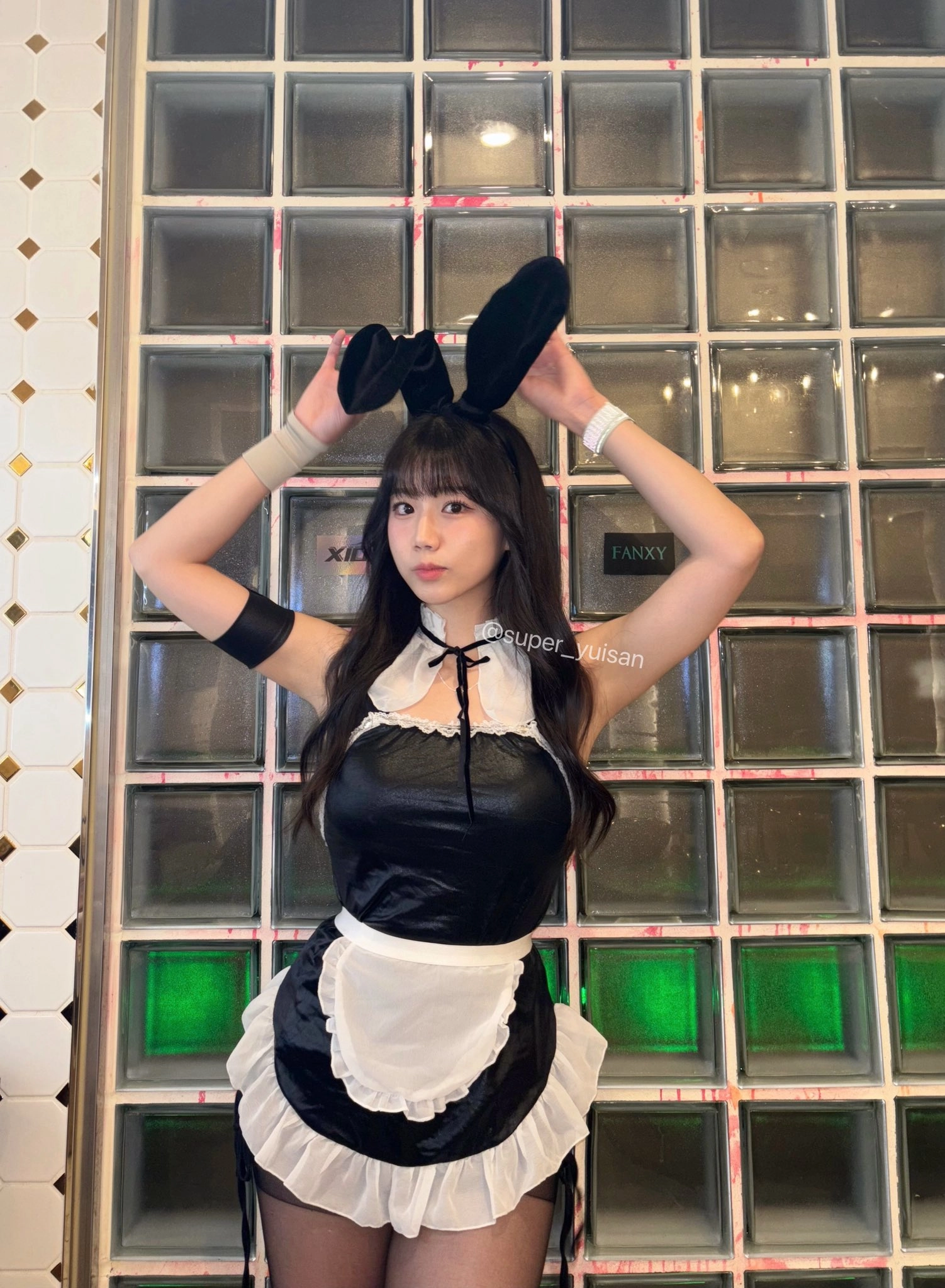 穿着黑色裙子和兔子耳朵的女人为一张照片。