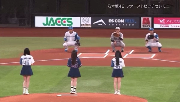 穿着棒球制服的女人站在一个球场上。