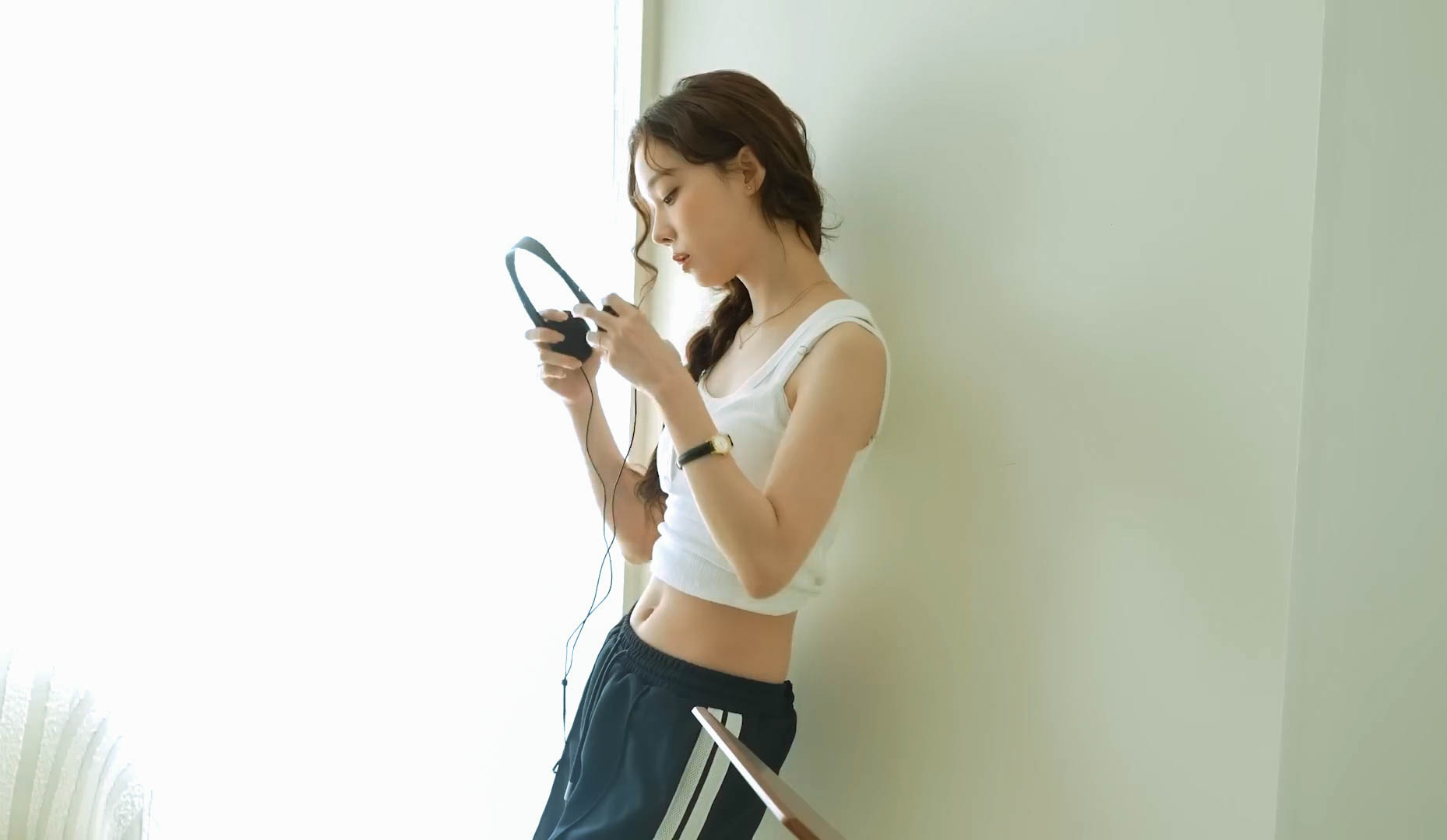 一位戴耳机和一件白色衬衫的女人坐在沙发上。