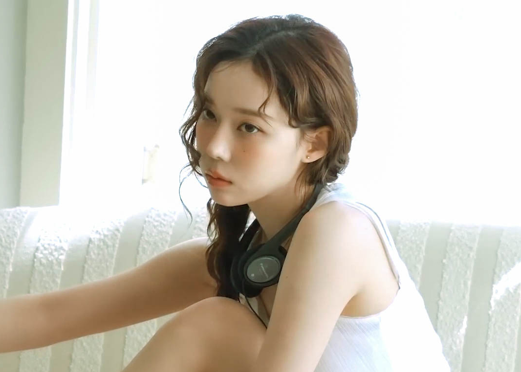 一位戴耳机和一件白色衬衫的女人坐在沙发上。