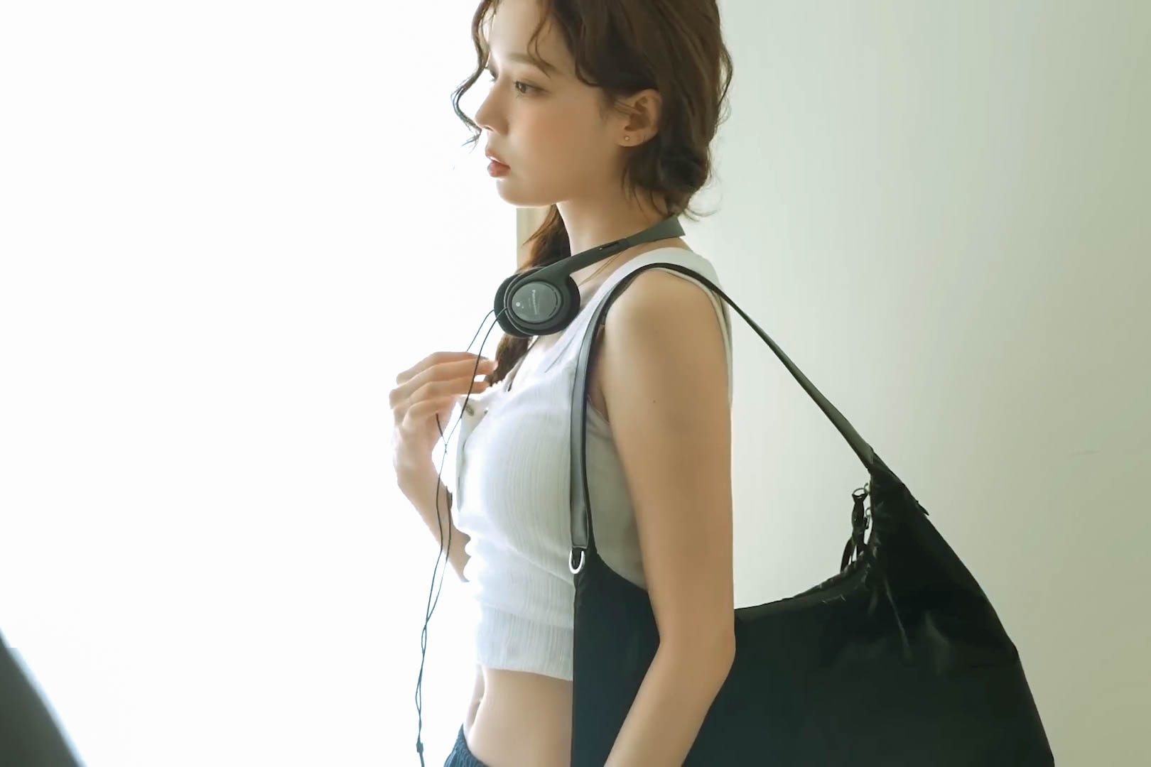 一位戴耳机和一件白色衬衫的女人坐在沙发上。