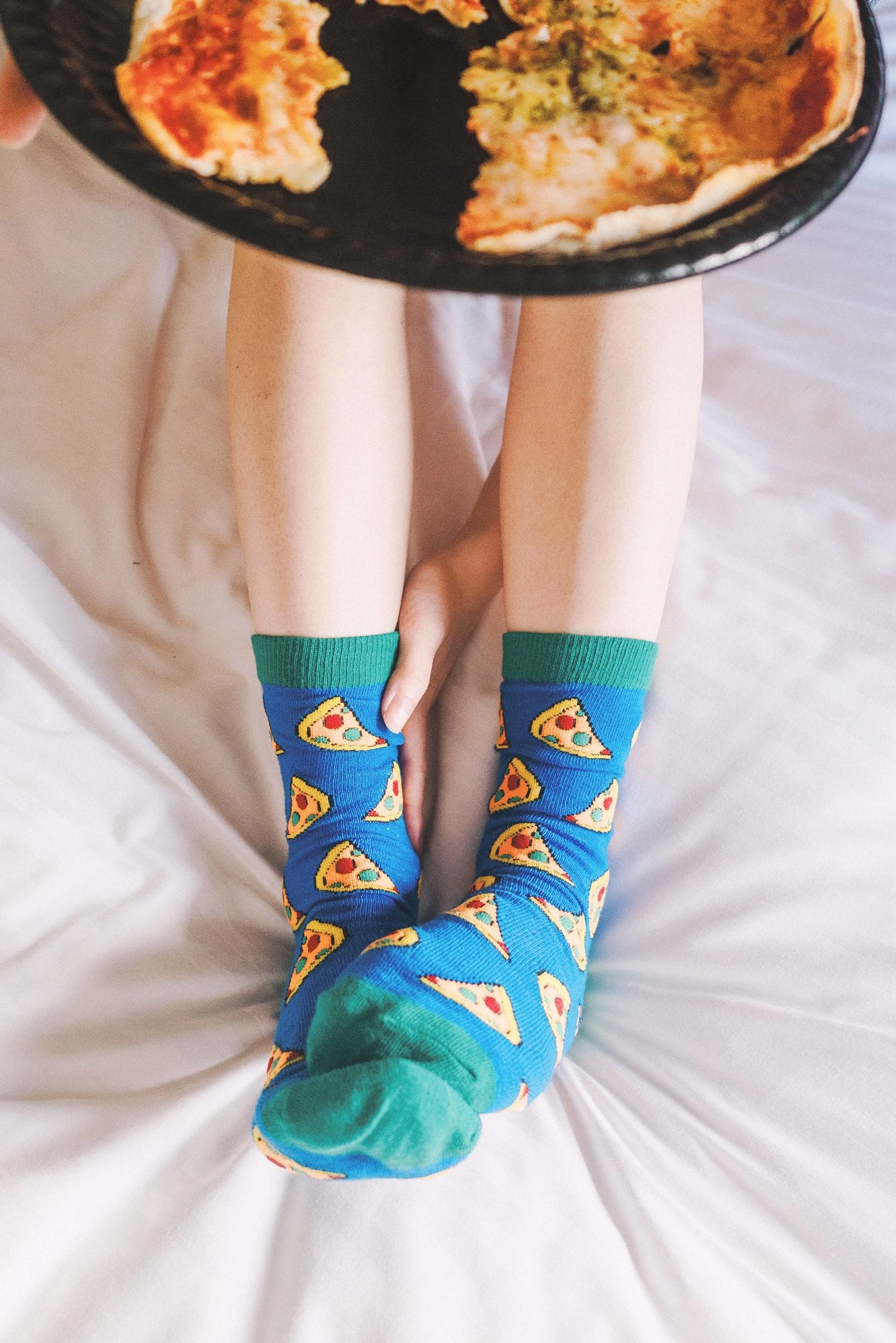 穿着绿色和蓝色袜子的人,上面有披萨。