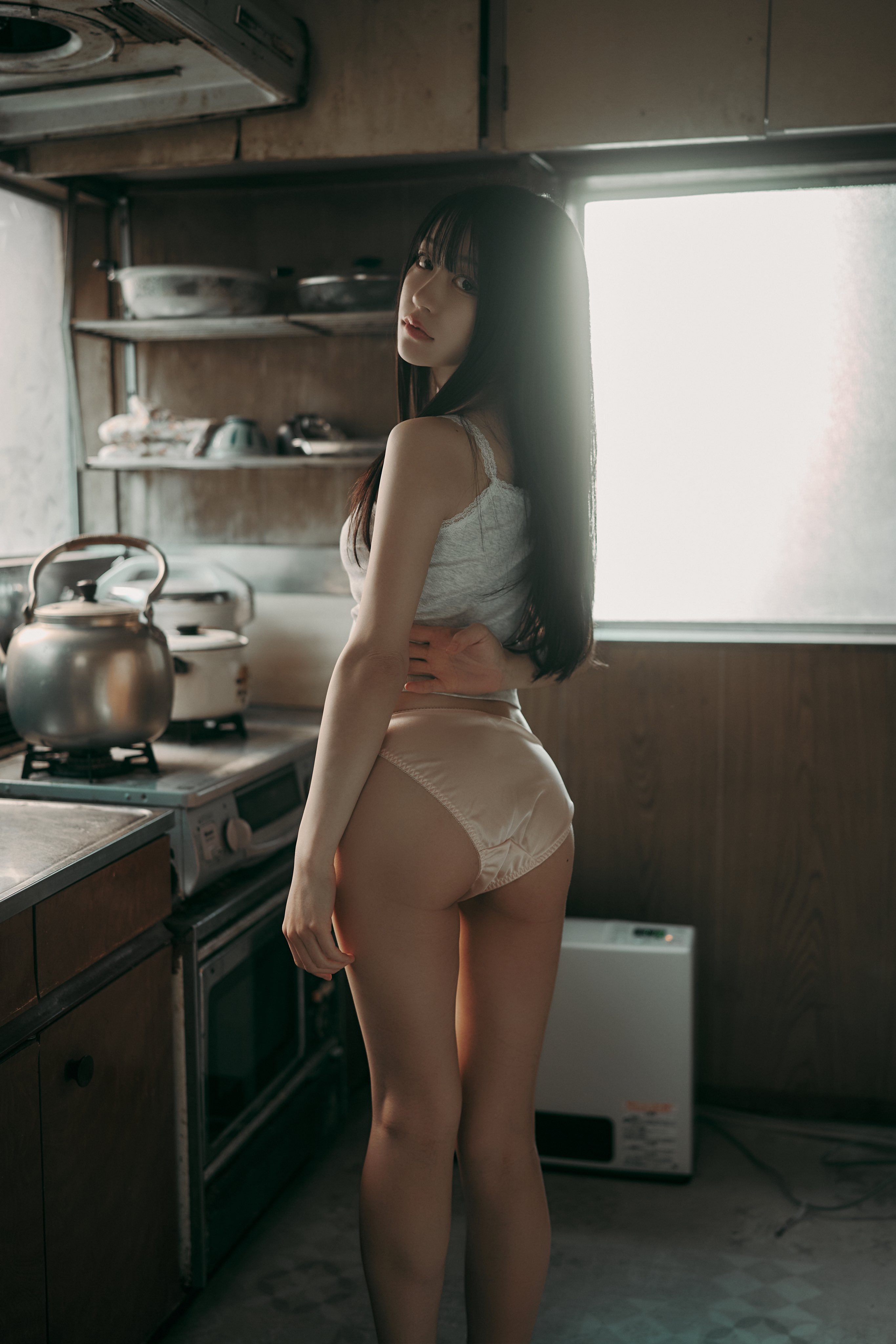 穿着胸罩和裤子的女人在厨房里姿势。