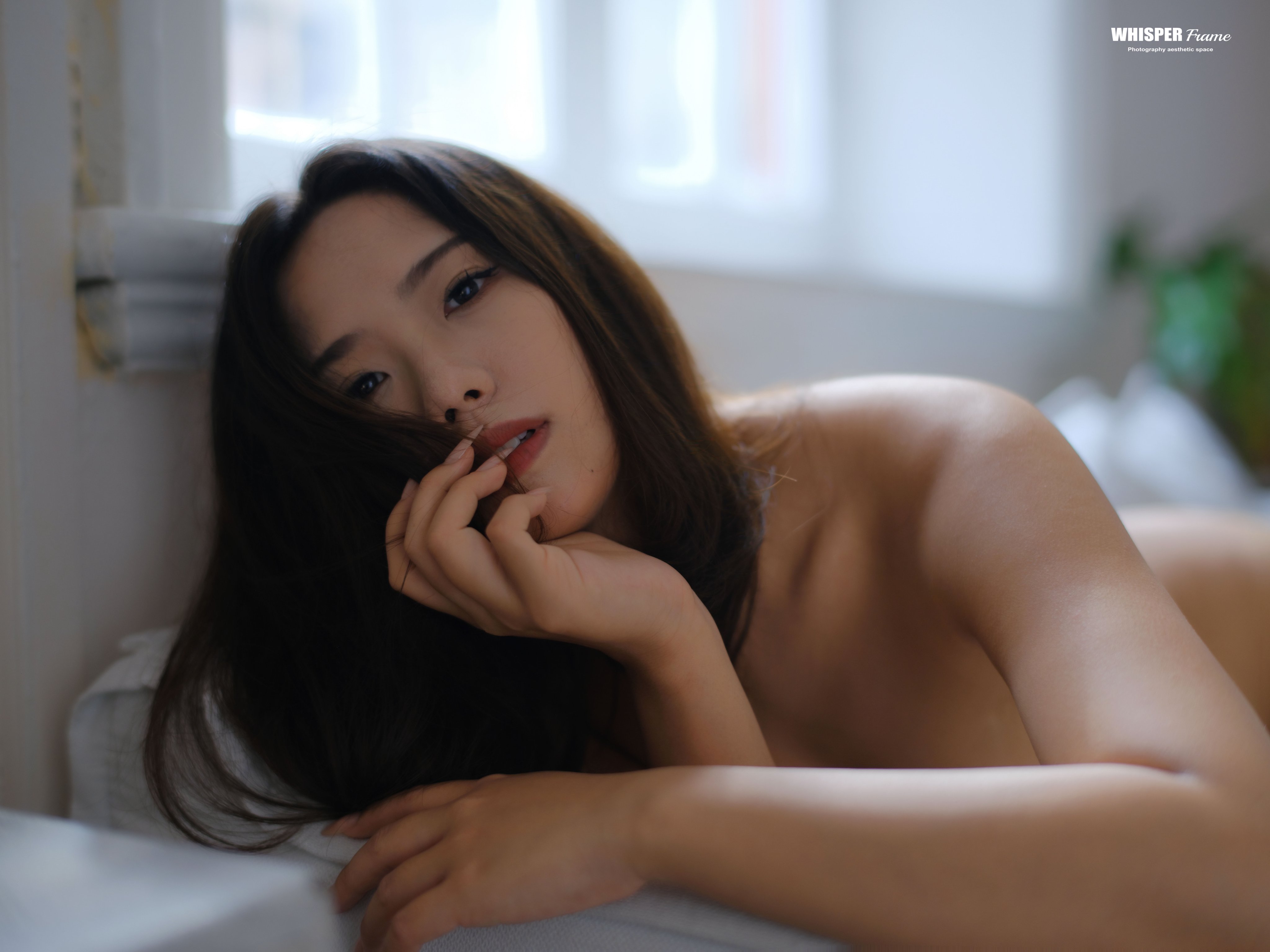 女人躺在沙发上,Topless,她的手放在胸前。