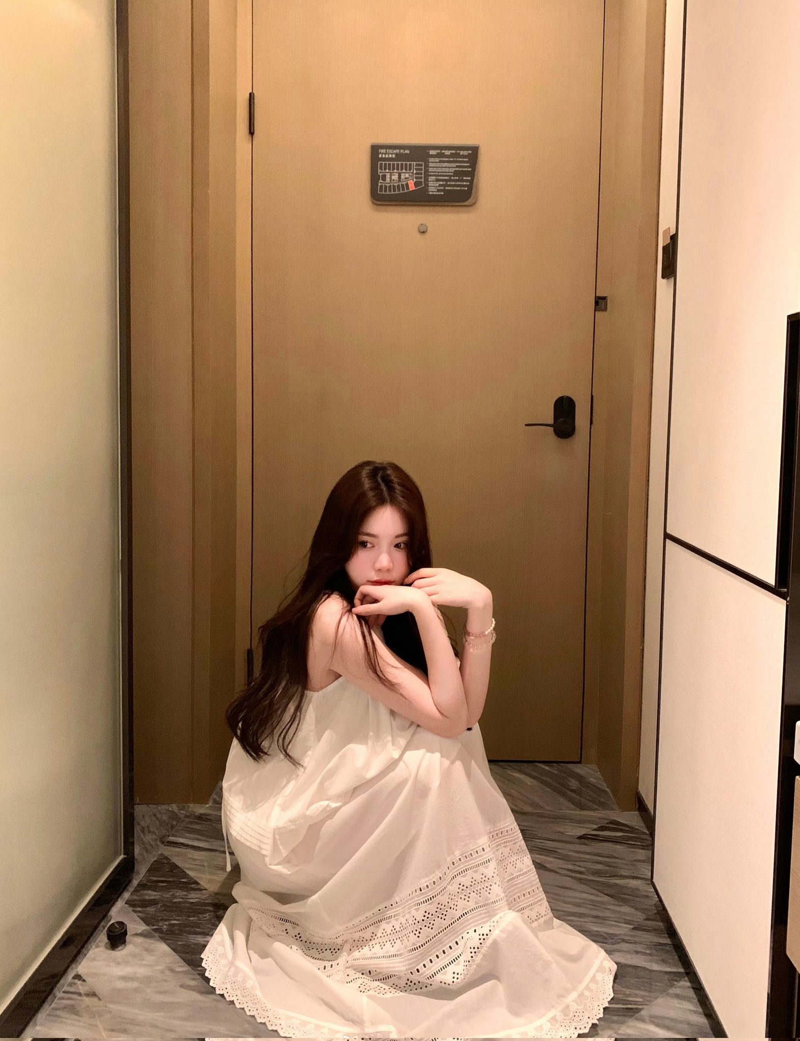 穿白衣的女人坐在地板上。