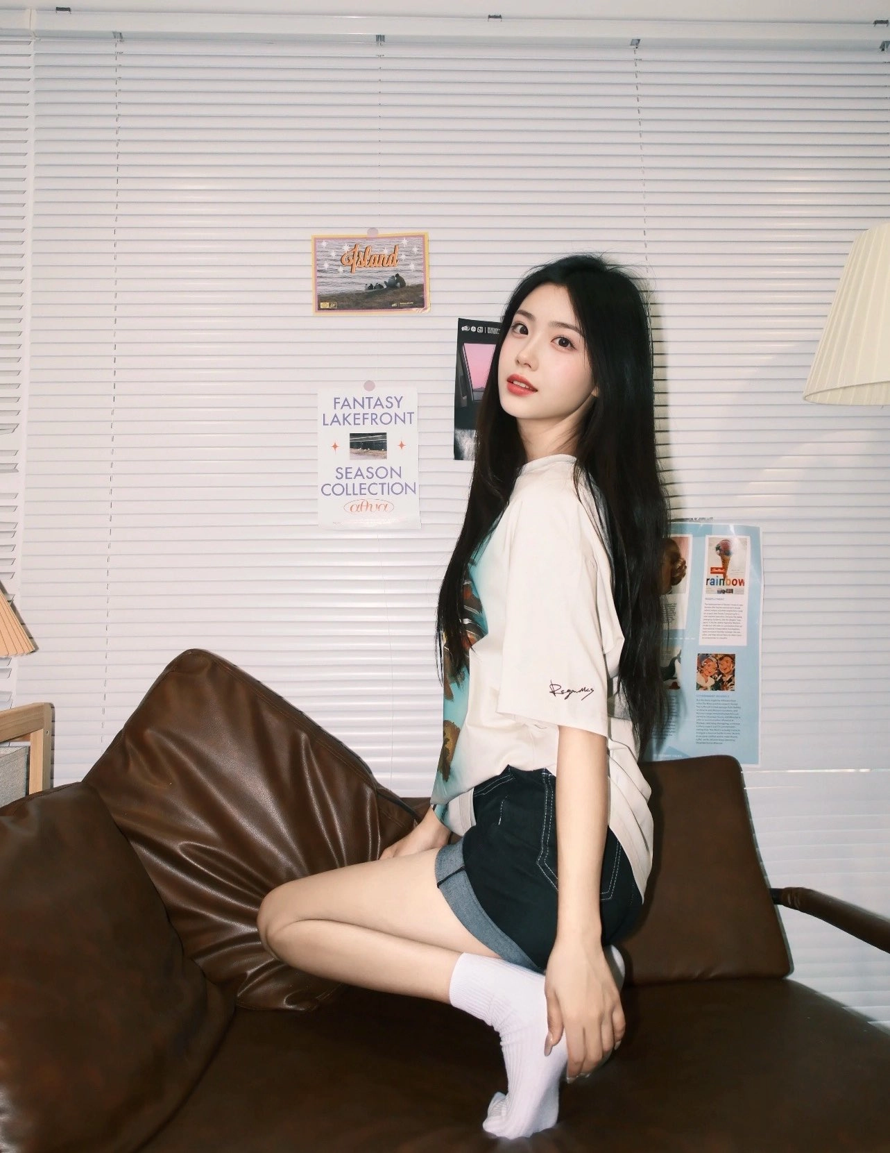 女人坐在一张沙发上,墙上有一张海报。