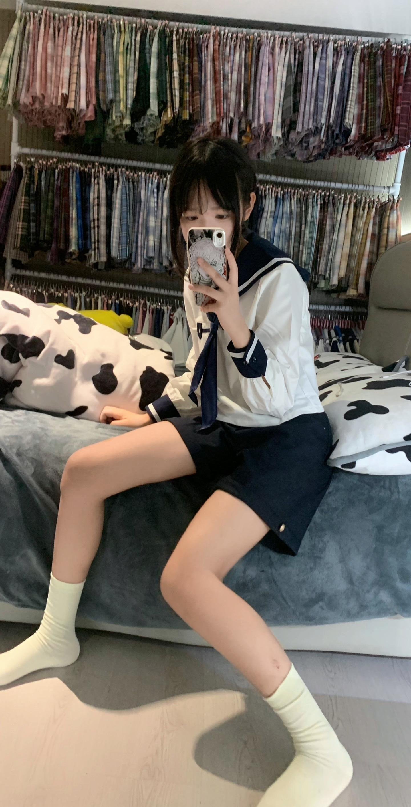 一位穿着白色衬衫和蓝色裙子的女人坐在床上。