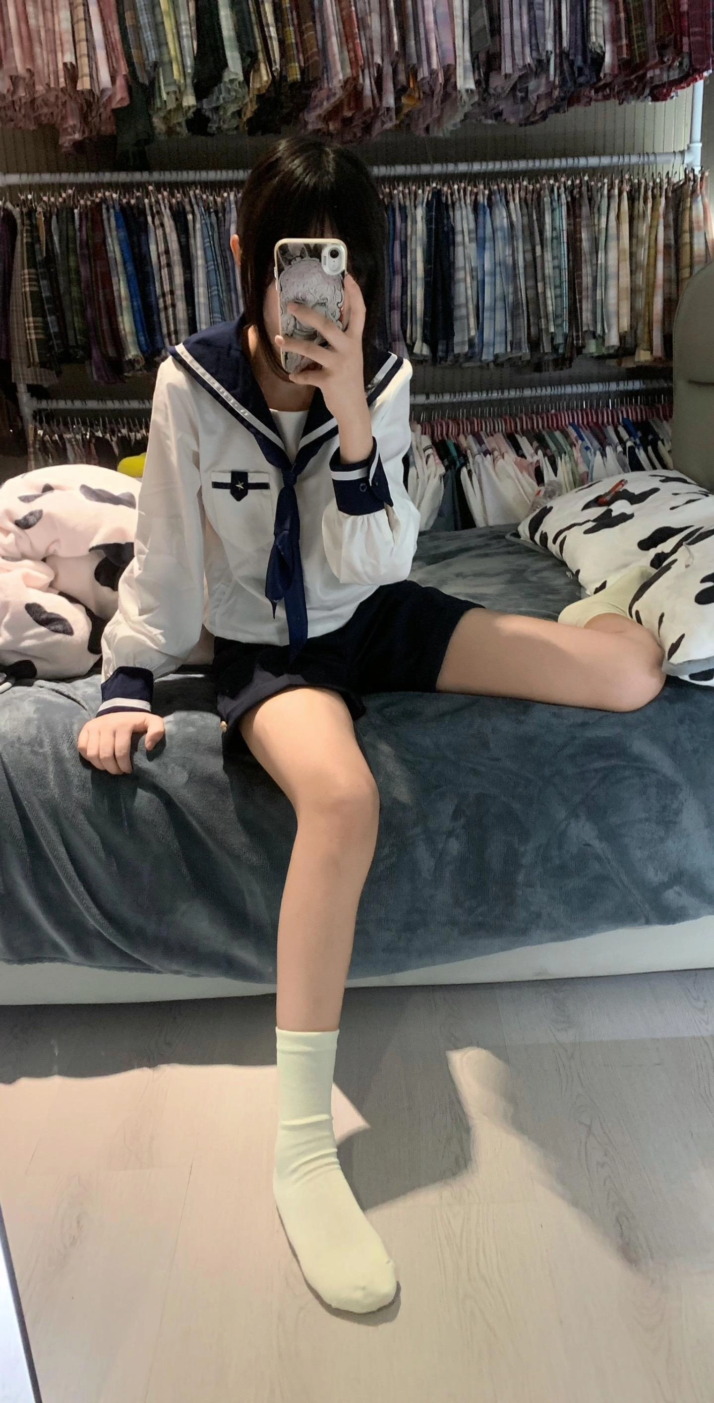 一位穿着白色衬衫和蓝色裙子的女人坐在床上。