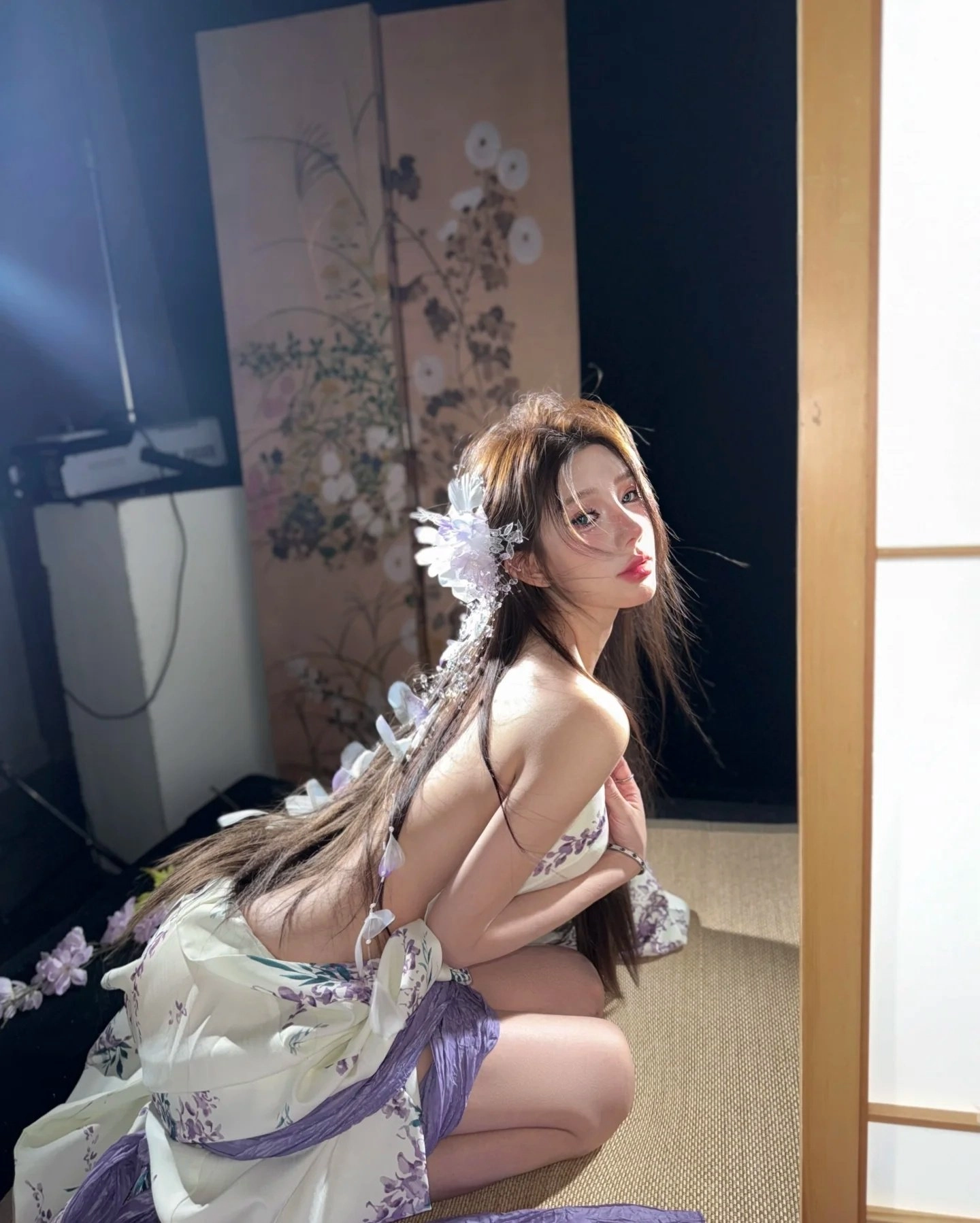 女人在头发上穿着一朵白色的花,为一张照片而立场。