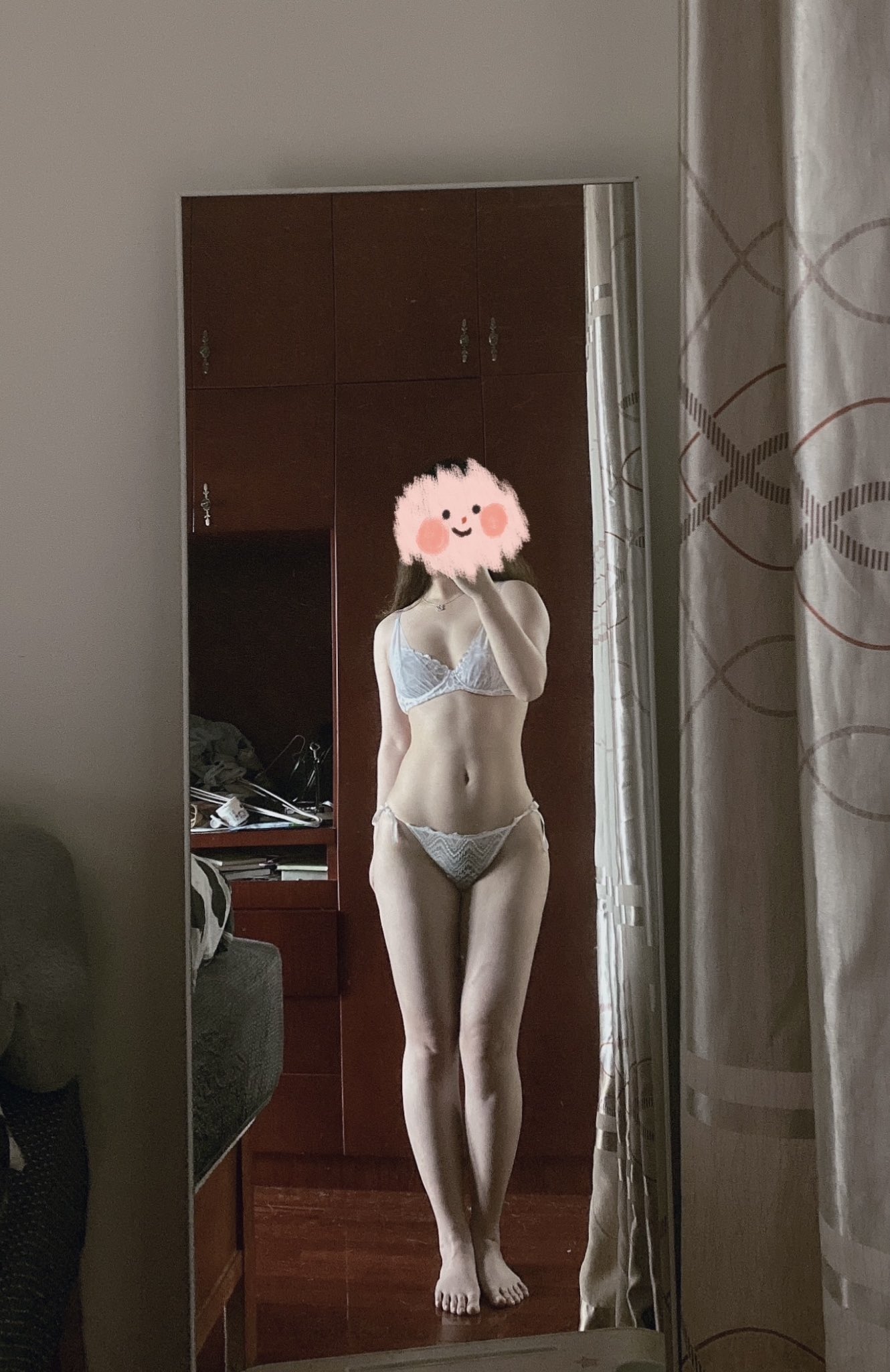 一位穿着白色胸罩和裤子的女人在镜子前拍自拍。