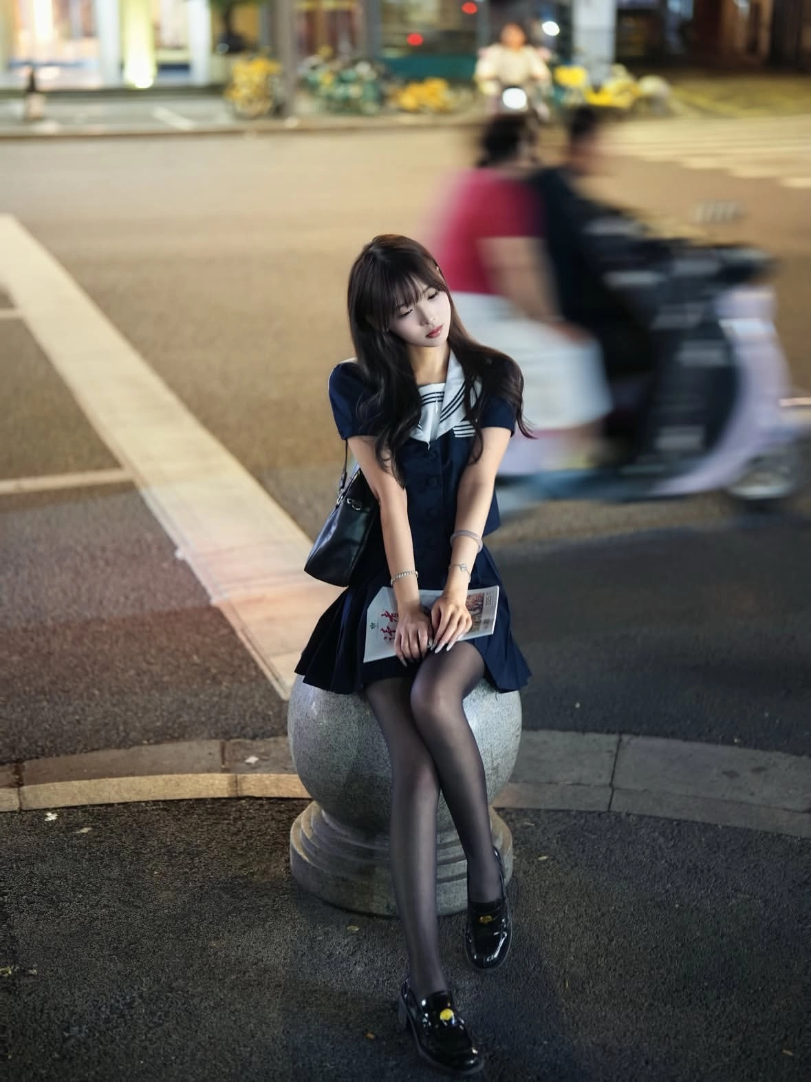 女人坐在一个圆形的物体上,拿着一本书。