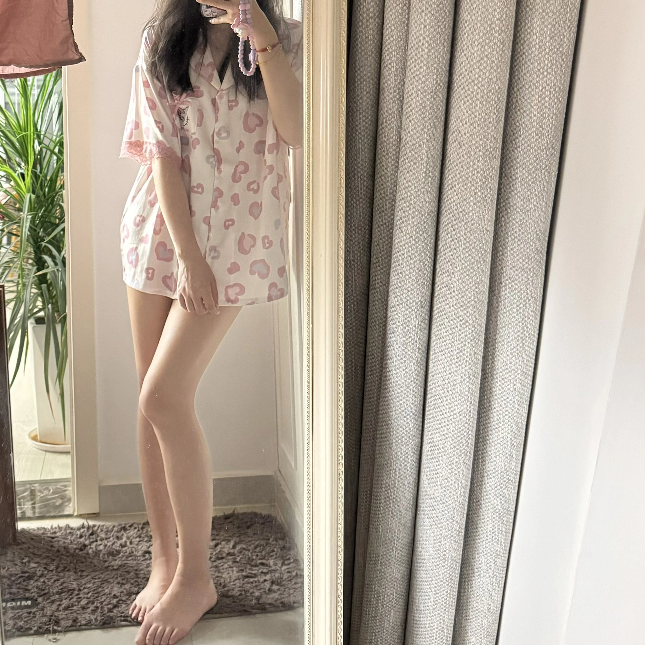 穿着粉红色衬衫和粉红色短裤的女人在镜子前拍自拍。