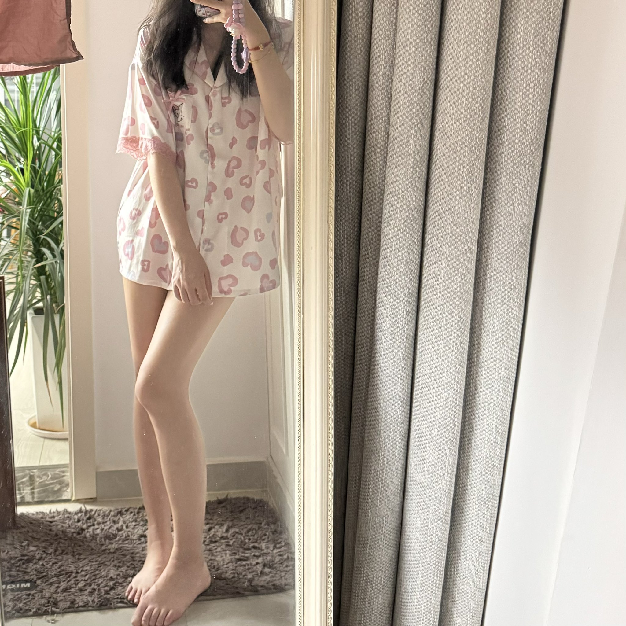 穿着粉红色衬衫和粉红色短裤的女人在镜子前拍自拍。