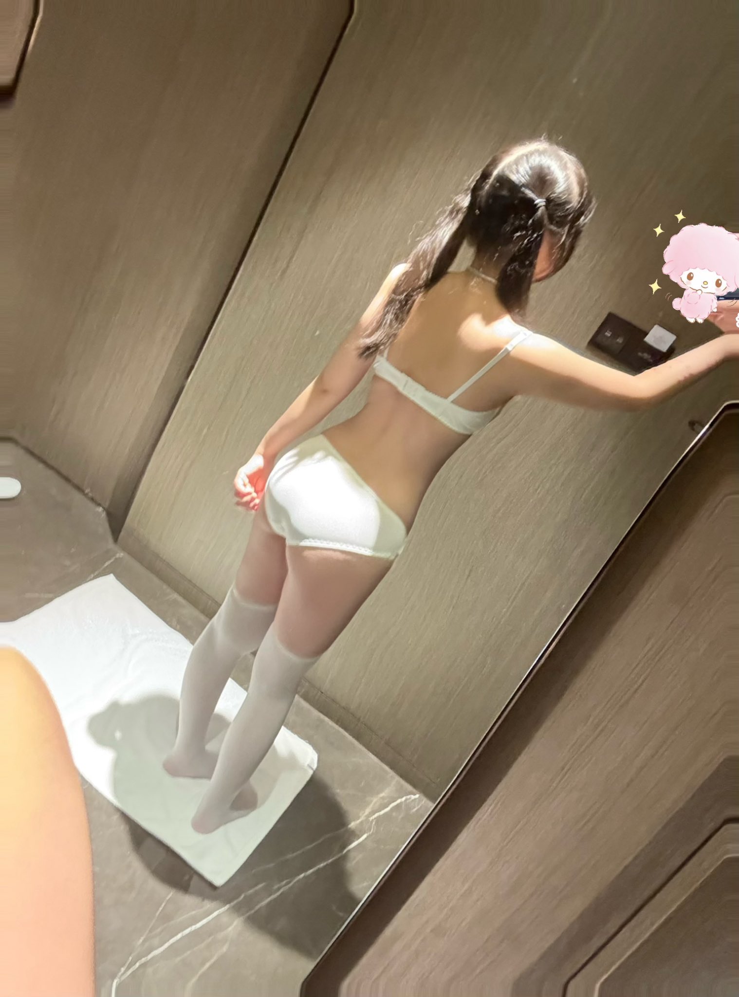 穿着白色衣服的女人在镜子里拍了一张自拍。