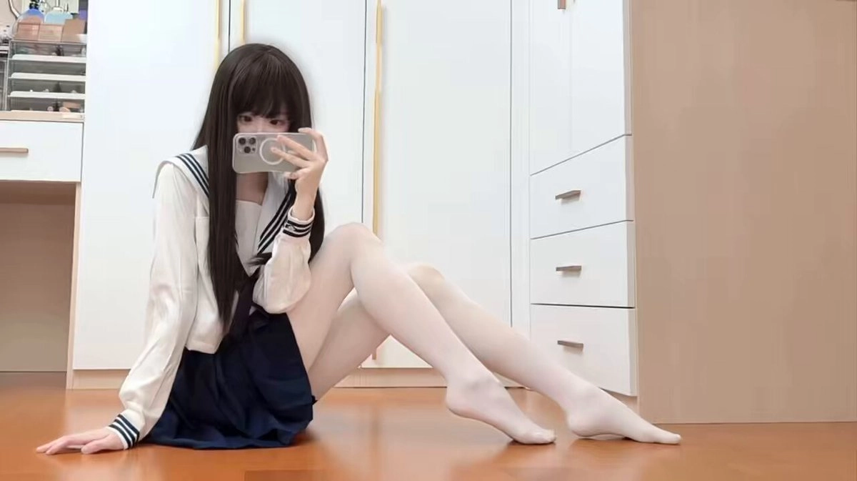 一位穿着白色夹克和蓝色裙子的女人正在拍照自己。