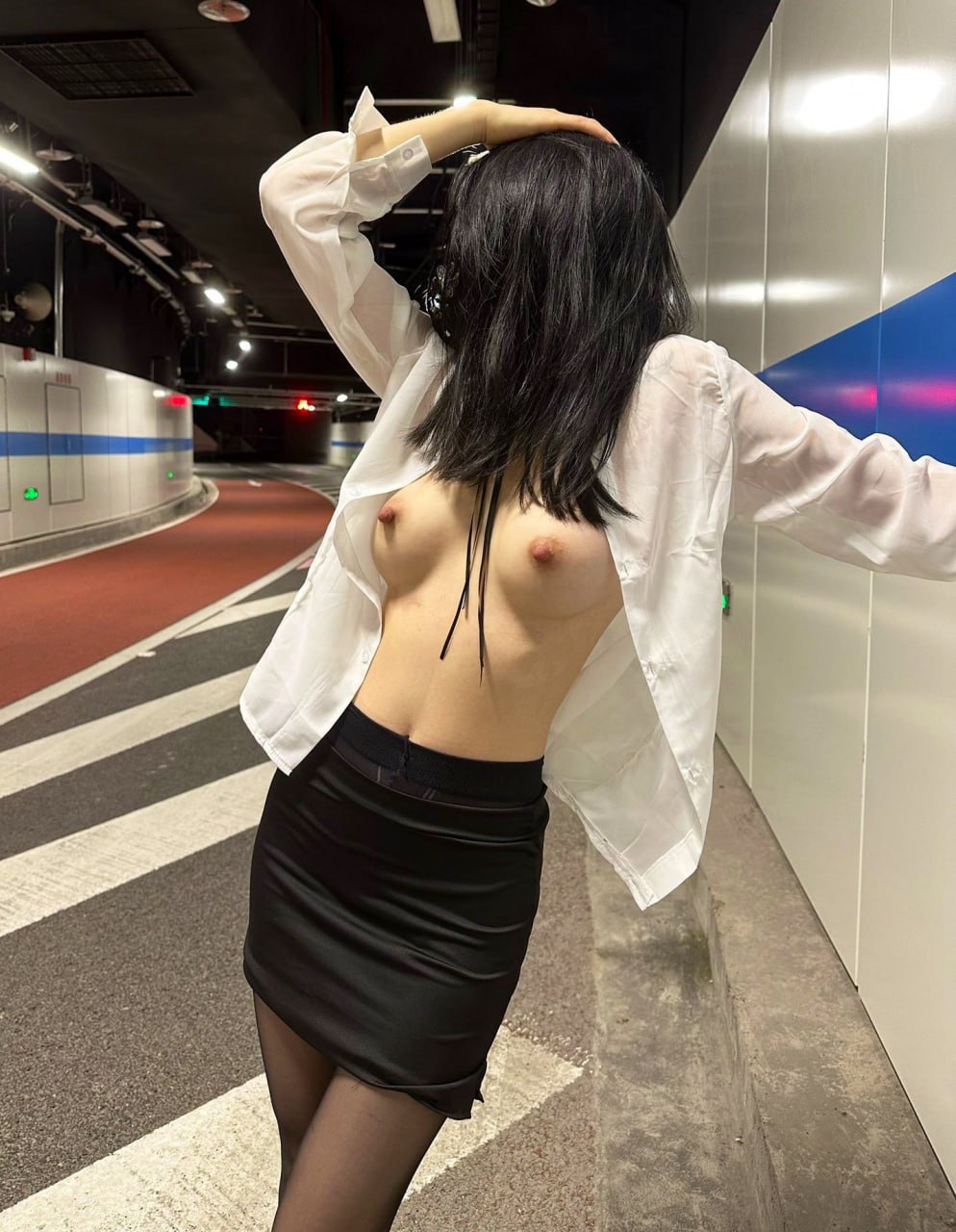 一位穿着白色衬衫和黑色裙子的女人站在街上。