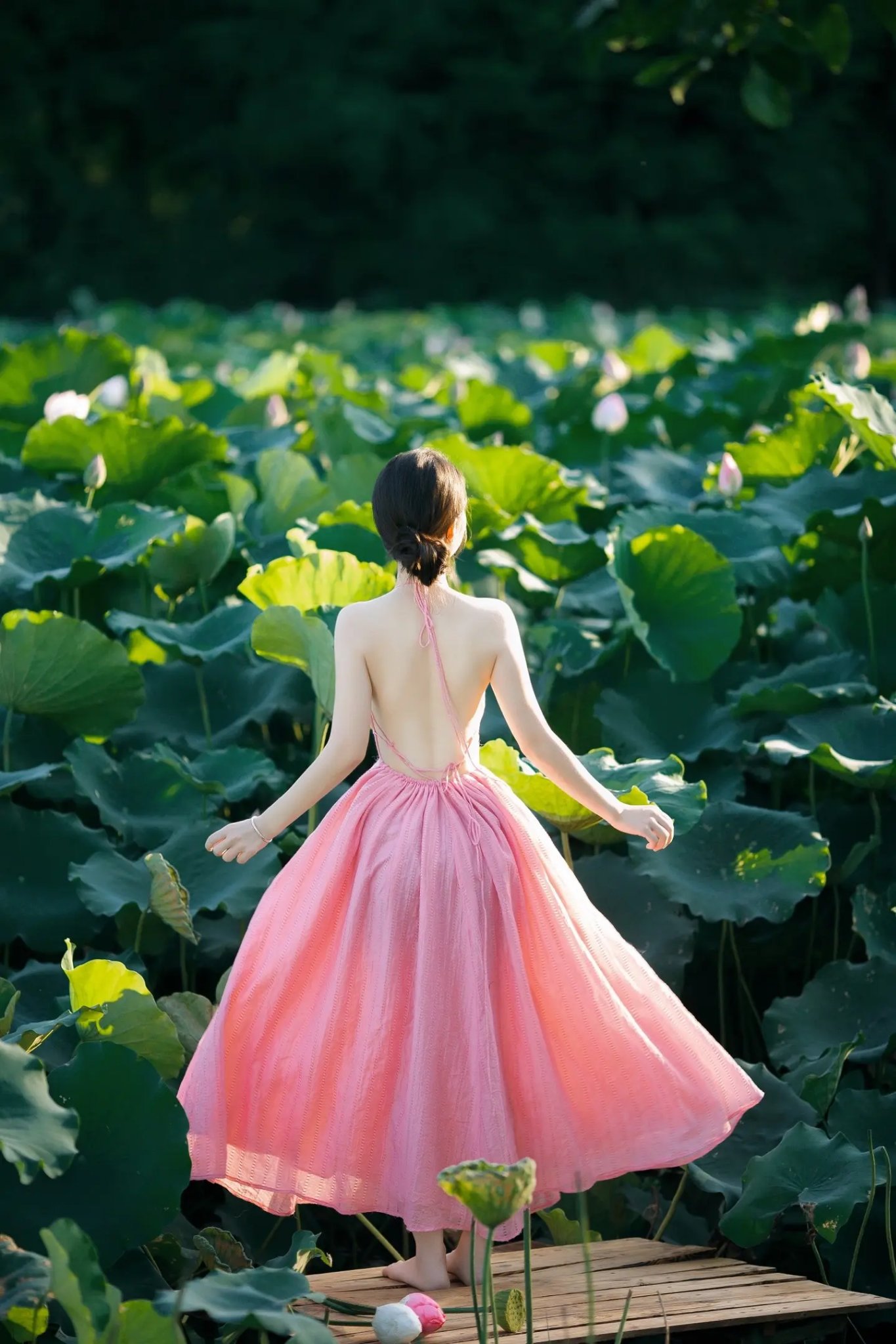 一位穿着粉红色衣服的女人穿过一片花的田野。