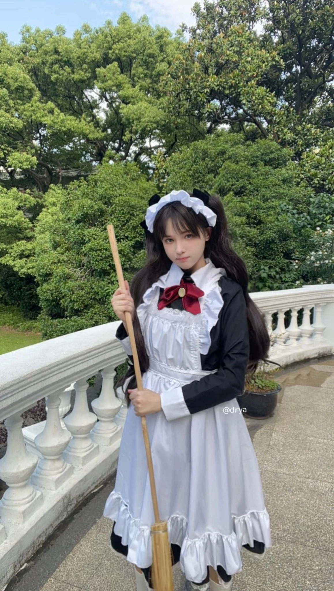 一位女士穿着女仆的服装,拿着一根子。