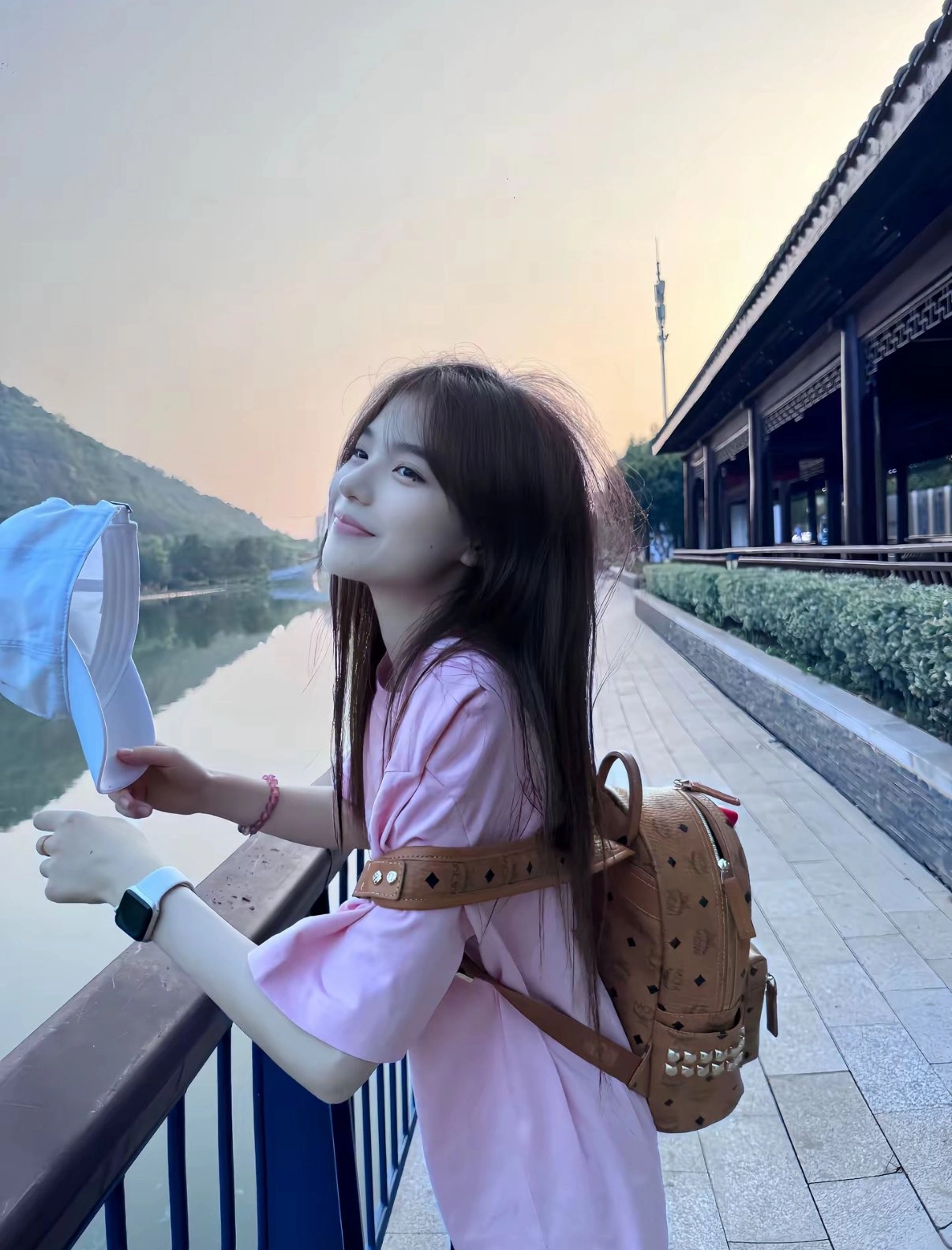 一位穿着粉红色衬衫和棕色背包的女人微笑着。