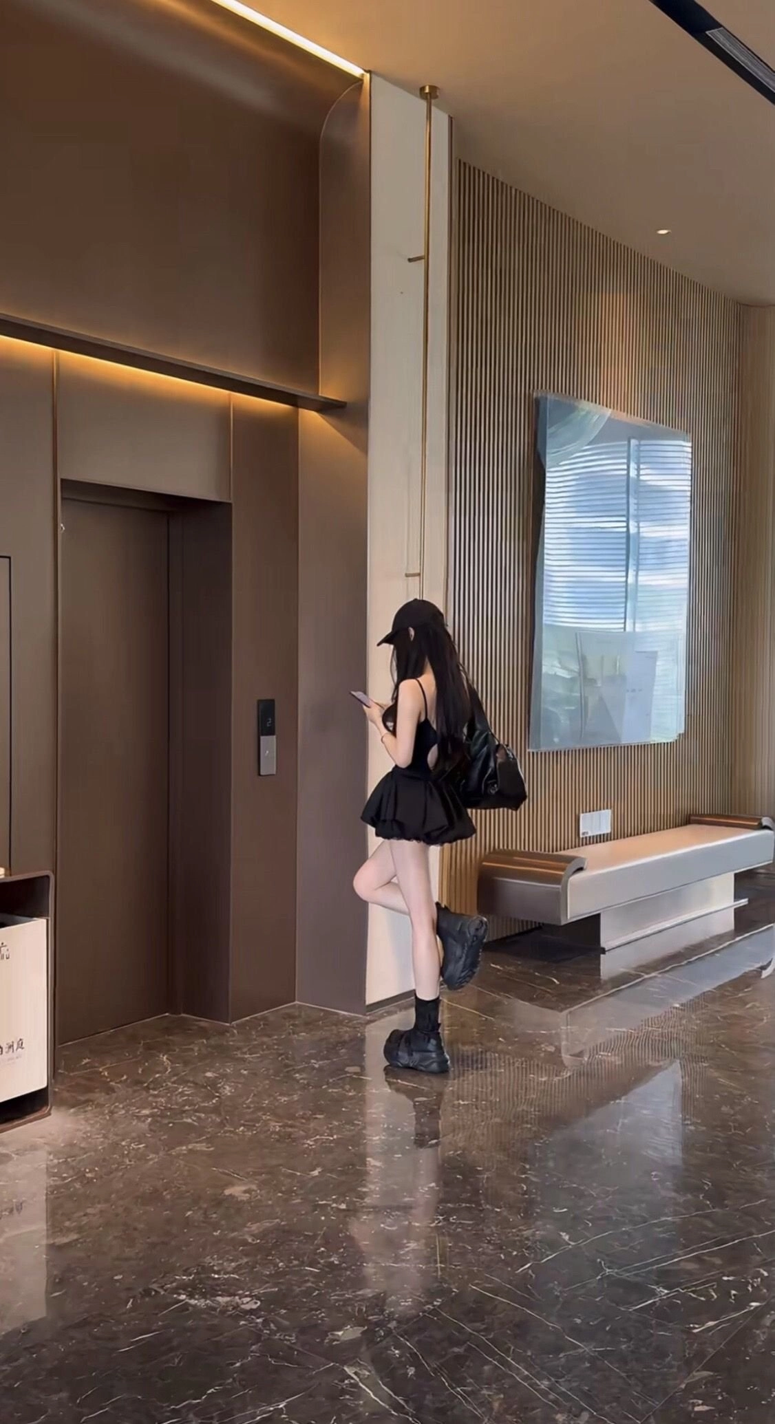 一位穿着黑色衣服的女人在走廊上写短信。