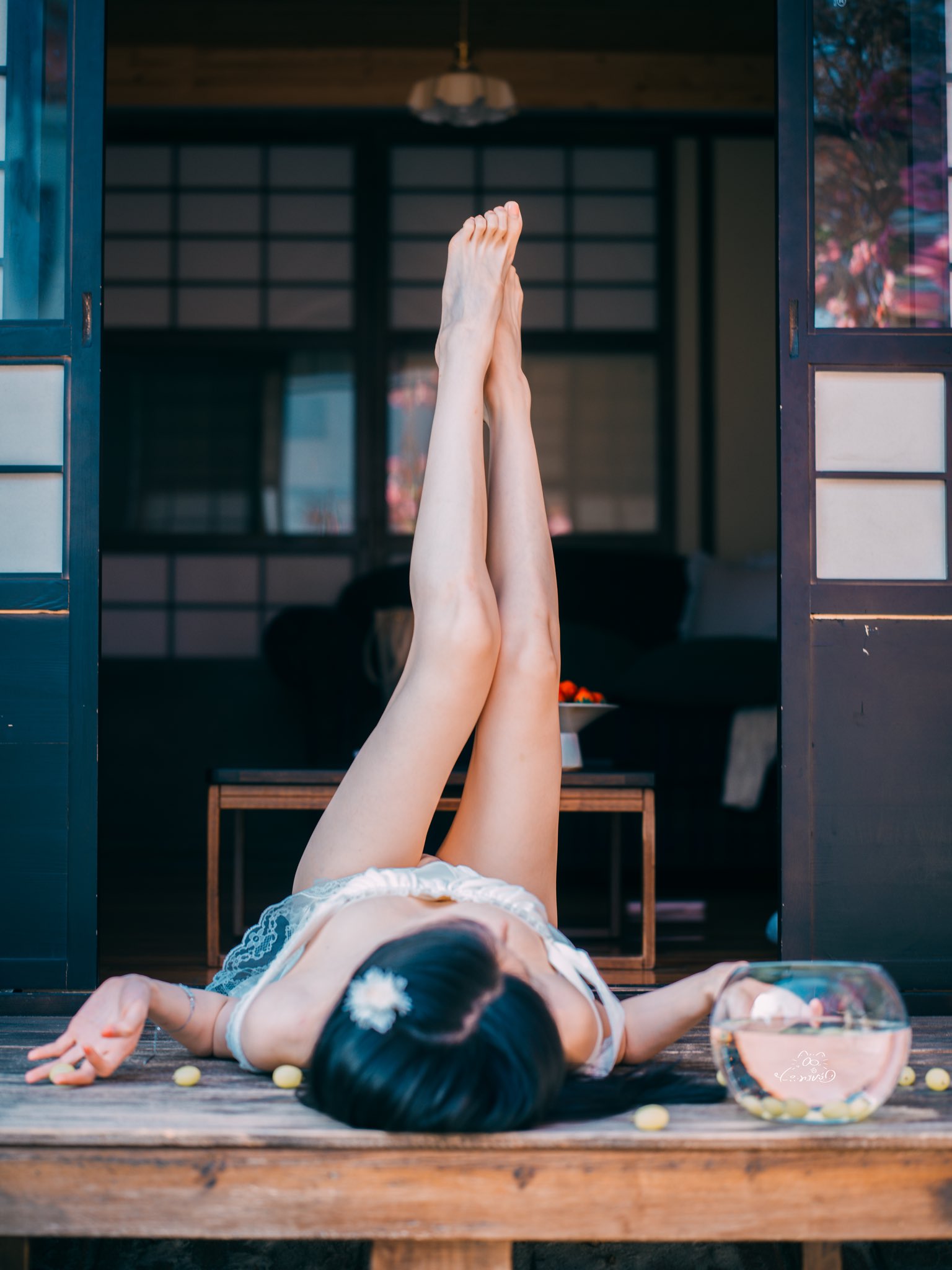 女人坐在沙发上,手臂围着腿,一碗葡萄在她面前。