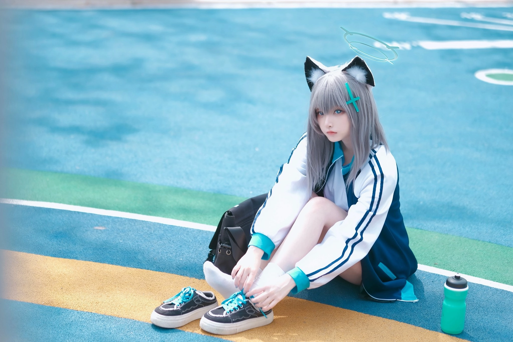 戴着猫类的帽子和蓝色夹克的女人坐在地上。