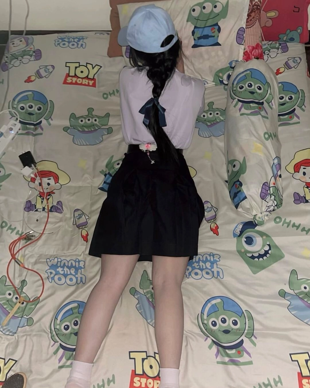 穿着马尾巴的女孩躺在一张玩具故事舒适器的床上。